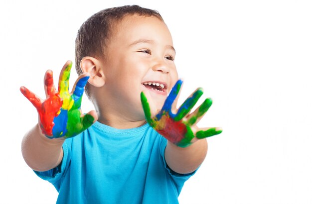 Criança de sorriso com as mãos cheias de tinta