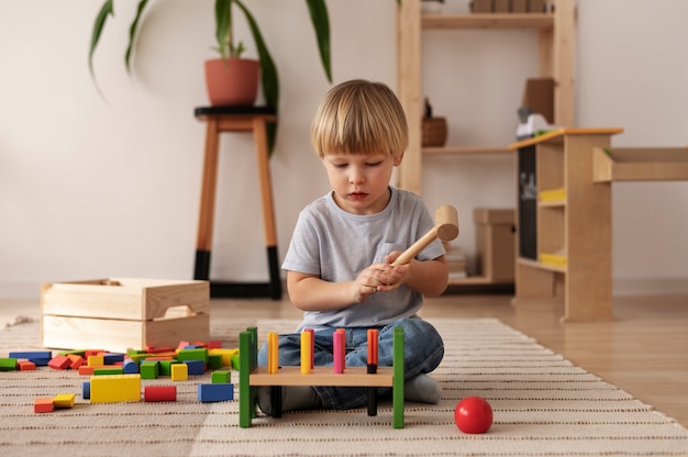Foto grátis criança de tiro completo brincando com brinquedos de madeira coloridos