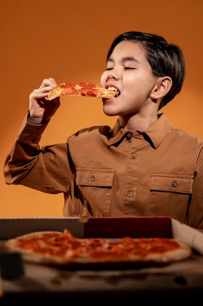 Criança de tiro médio comendo pizza