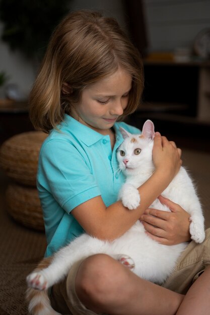 Criança de tiro médio segurando um gato branco