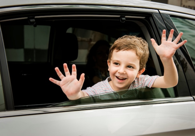 Criança do menino no cumprimento de sorriso alegre do carro