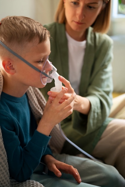 Foto grátis criança doente de vista lateral usando um nebulizador