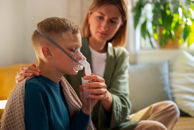 Foto grátis criança doente de vista lateral usando um nebulizador