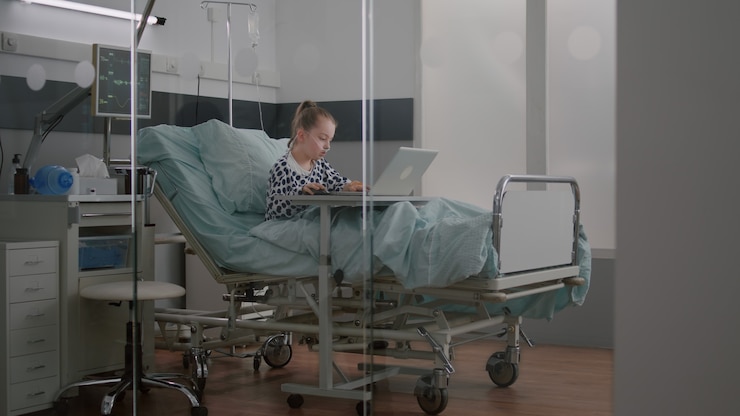 Foto grátis criança doente relaxando na cama jogando videogame de desenho animado no laptop durante o exame médico ...