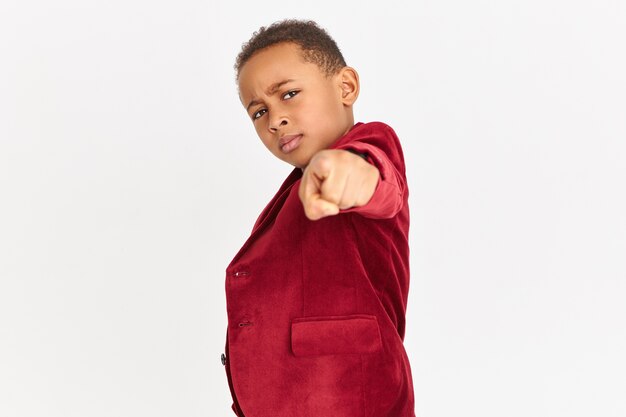 Criança elegante com blazer vermelho apontando para a frente