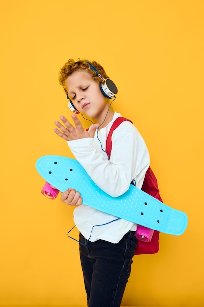 Criança elegante com skate em fones de ouvido, estilo de vida urbano ativo dos jovens Foto Premium