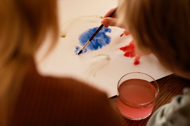 Foto grátis criança em close-up pintando em papel de alto ângulo