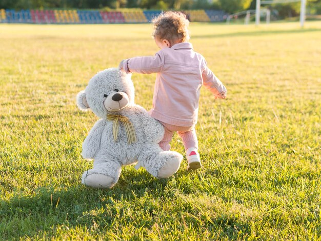 Criança em roupas cor de rosa e seu brinquedo amigável