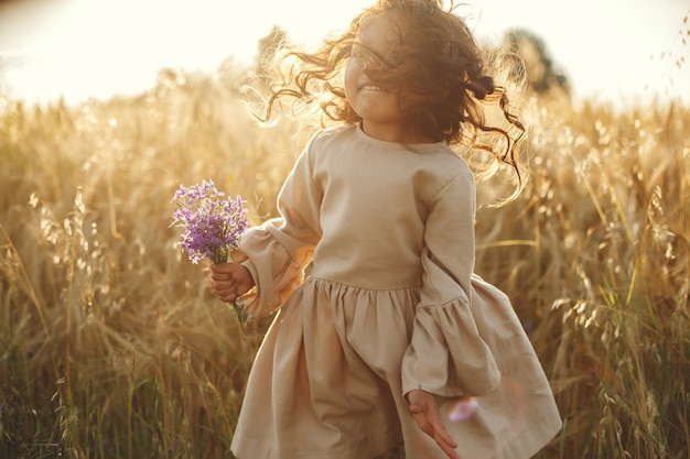 Foto grátis criança em um campo de verão. menina com um lindo vestido marrom.