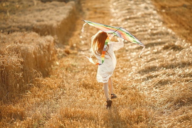 Criança em um campo de verão. menina em um lindo vestido branco. criança com uma pipa.