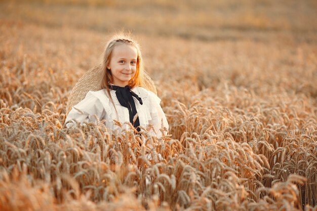 Criança em um campo de verão. Menina em um lindo vestido branco.