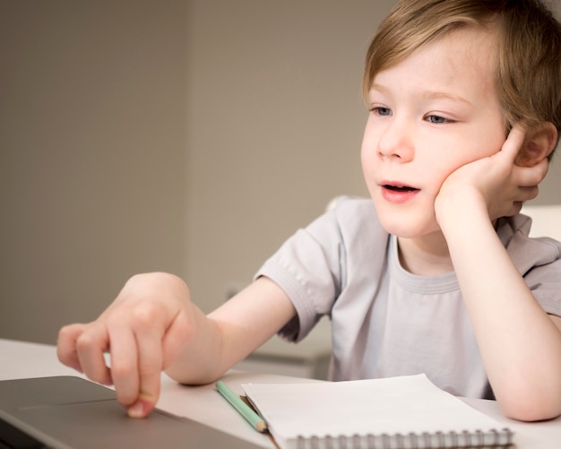 Criança entediada ouvindo aulas on-line