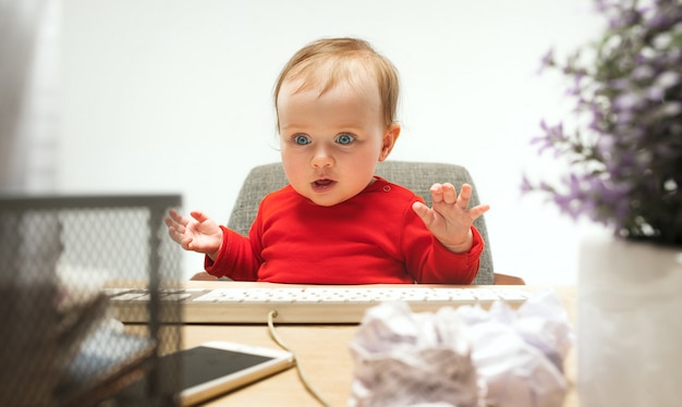 Criança feliz bebê menina criança sentada com o teclado do computador isolado