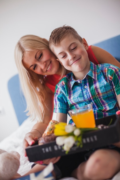 Criança feliz com bandeja do pequeno almoço para sua matriz