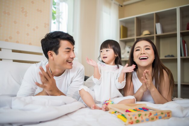 Criança feliz com os pais brincando na cama em casa