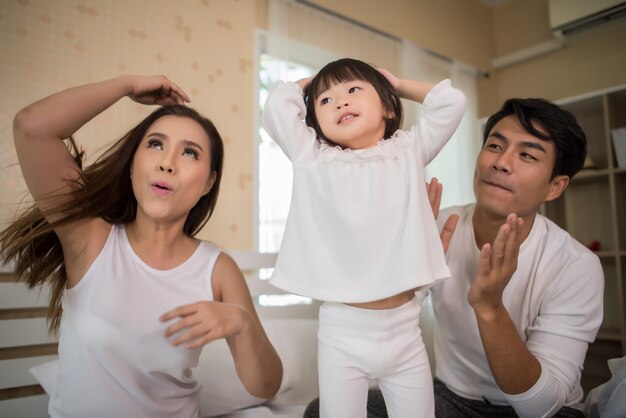 Criança feliz com os pais brincando na cama em casa