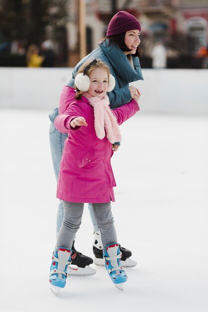 Criança feliz e mãe patinar no gelo