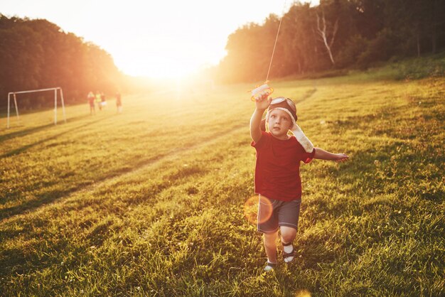 Criança feliz lançar uma pipa no campo ao pôr do sol. Menino e menina nas férias de verão
