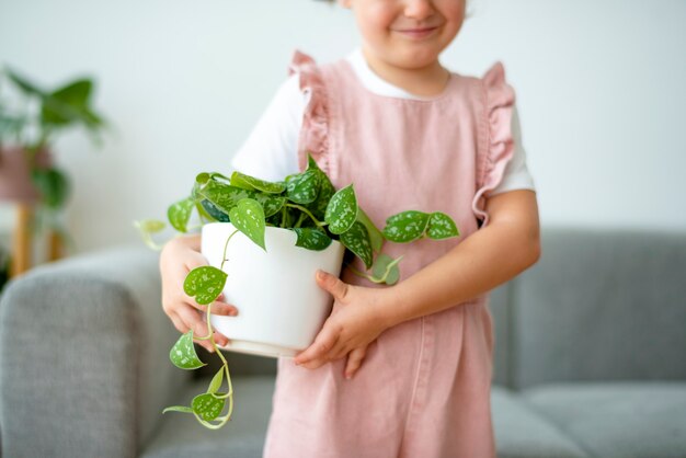Criança feliz segurando um pequeno vaso de planta em casa