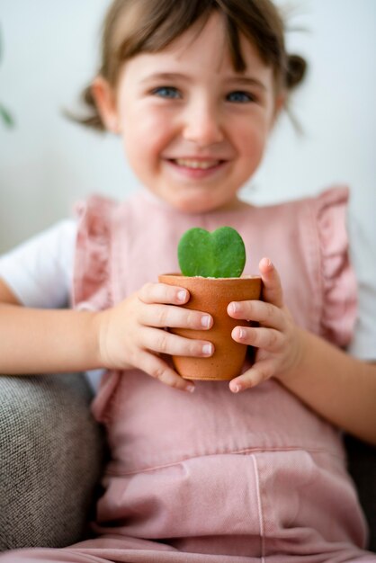 Criança feliz segurando um pequeno vaso de planta