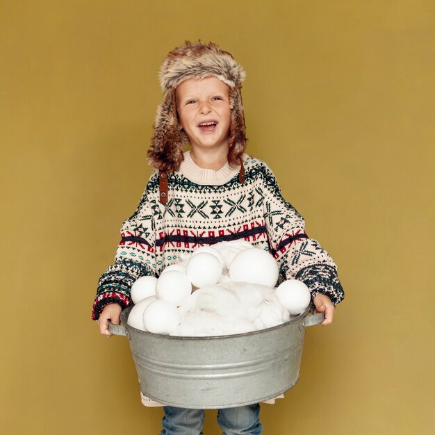 Foto grátis criança feliz vista frontal com chapéu e bolas de neve