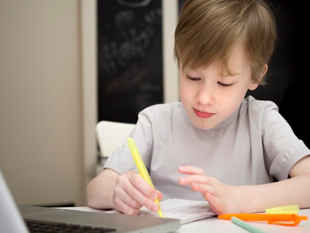 Criança focada, escrevendo em seu caderno tiro médio