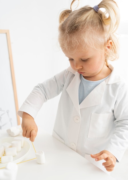 Foto grátis criança linda aprendendo ciência com marshmallows e massas