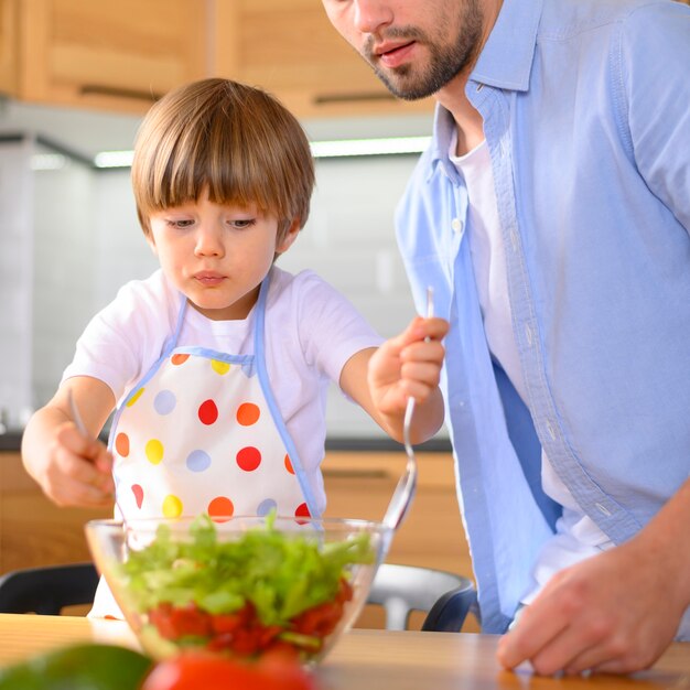 Criança mistura a salada da tigela