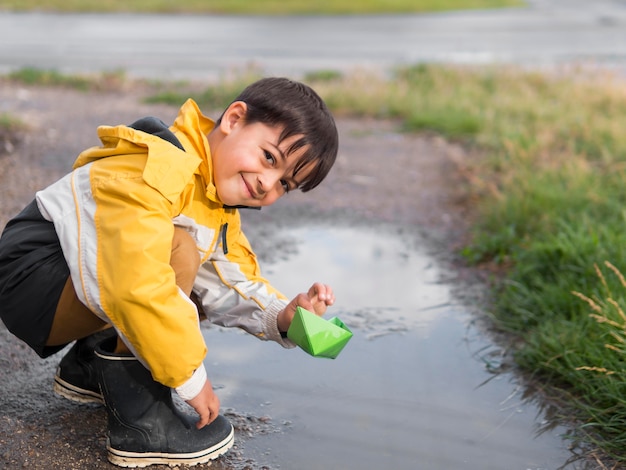 Criança na capa de chuva à beira do lago