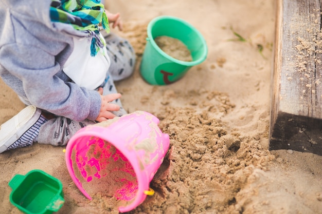 Criança que joga com areia