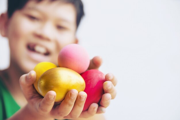 Criança que mostra ovos da páscoa coloridos felizmente - conceito da celebração do feriado da Páscoa