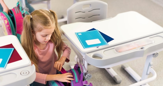Criança segurando material escolar na mochila