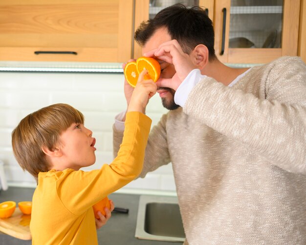 Criança segurando metades de laranjas para seu pai