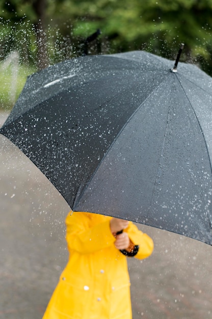 Foto grátis criança segurando um grande guarda-chuva preto