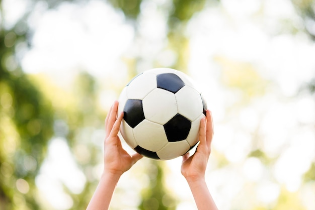 Criança segurando uma bola de futebol no ar