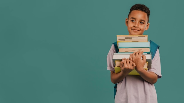 Criança segurando uma pilha de livros, cópia de espaço