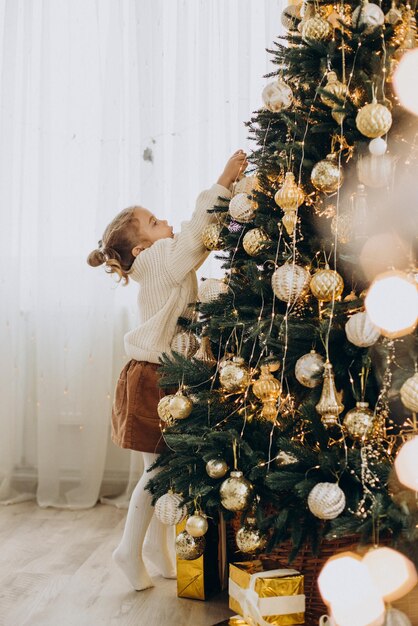 Criança sentada debaixo da árvore de natal