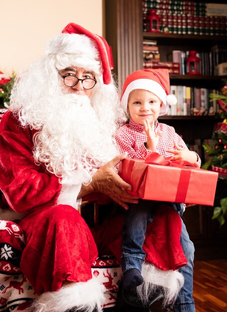 Criança sentada em um Papai pernas no natal