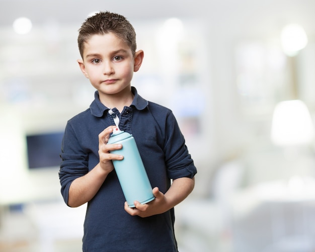 Criança séria com uma lata de spray