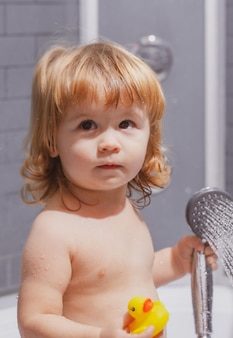Criança tomando banho em espuma de sabão bebê criança lavando em um banheiro em espuma
