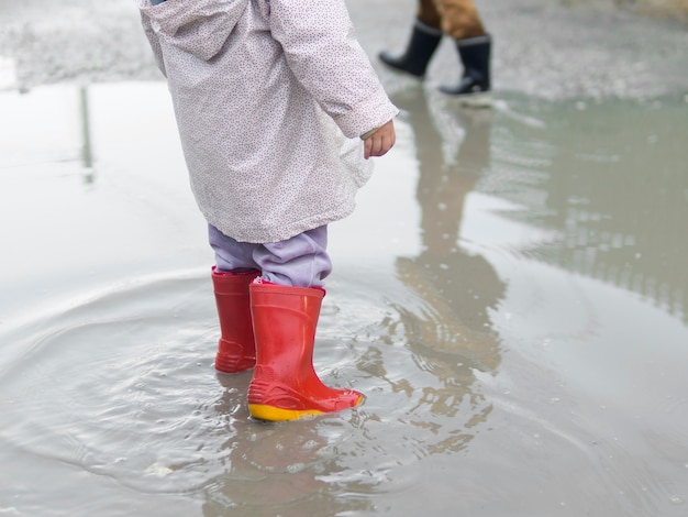 Foto grátis criança usando botas e sentado na água