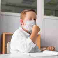 Foto grátis criança usando uma máscara médica na sala de aula