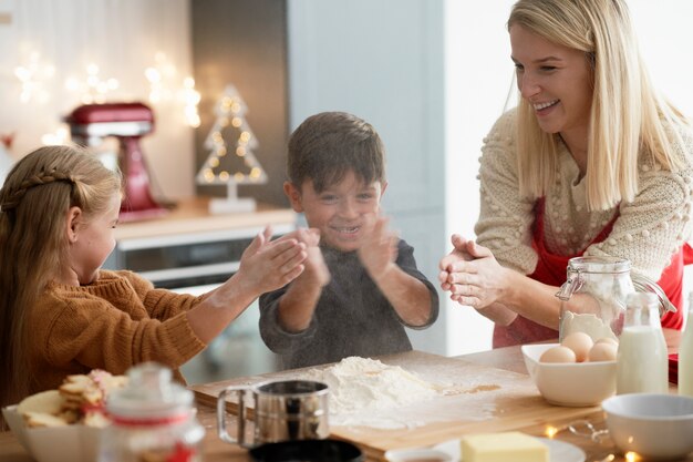 Crianças agarrando com farinha enquanto assam biscoitos