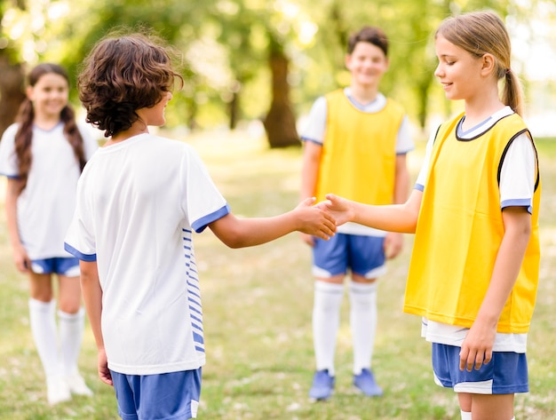 Crianças apertando as mãos antes de uma partida de futebol