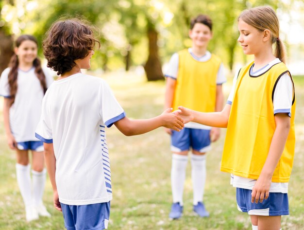 Crianças apertando as mãos antes de uma partida de futebol
