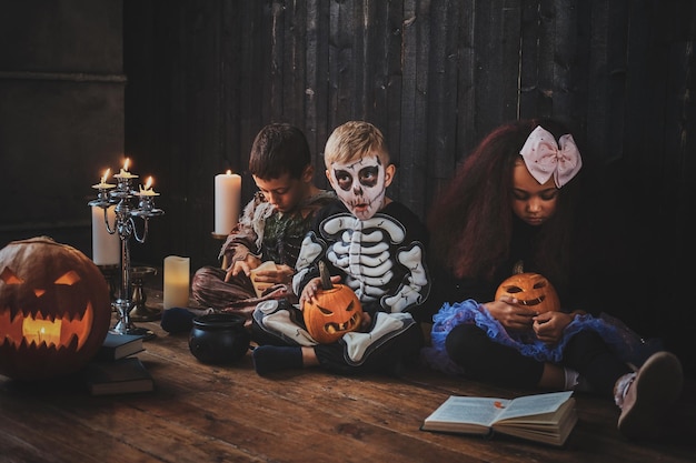 Crianças bonitas em trajes de Halloween estão curtindo a festa enquanto lêem o livro.