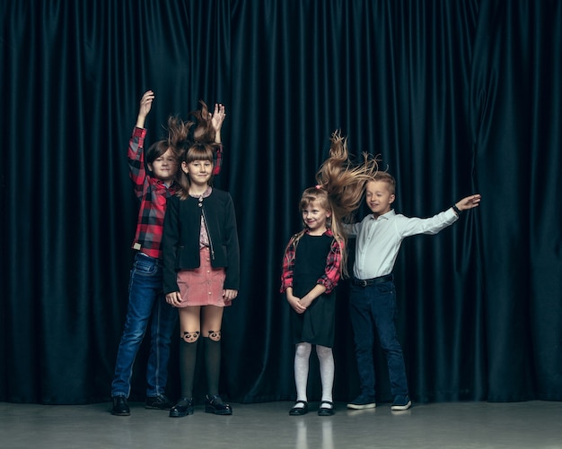 Crianças bonitos e elegantes no estúdio escuro. As lindas meninas adolescentes e meninos juntos