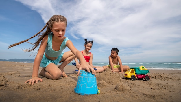 Foto grátis crianças brincando na praia tiro completo