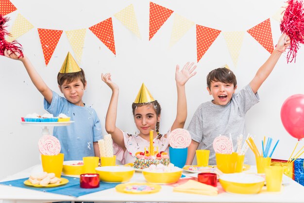 Crianças celebrando festa de aniversário em casa com variedade de comida na mesa