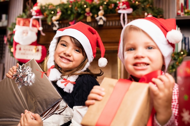 Crianças com presentes e chapéus de Santa